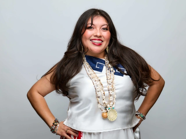 Women with brown hair in Tribal regalia smiling in confident pose.